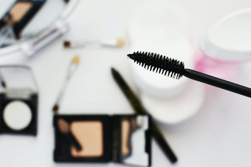 close-up of a mascara wand with makeup in background